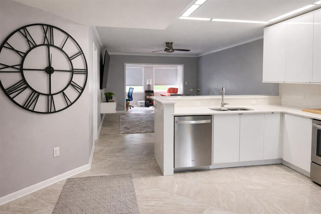 A kitchen with white cabinets and stainless steel appliances opens into a living area — 8651 10TH STREET N UNIT 228, ST PETERSBURG, FL