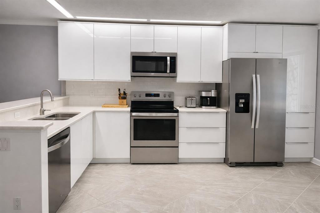 A modern kitchen features white cabinets, stainless steel appliances, and light-colored tile flooring — 8651 10TH STREET N UNIT 228, ST PETERSBURG, FL