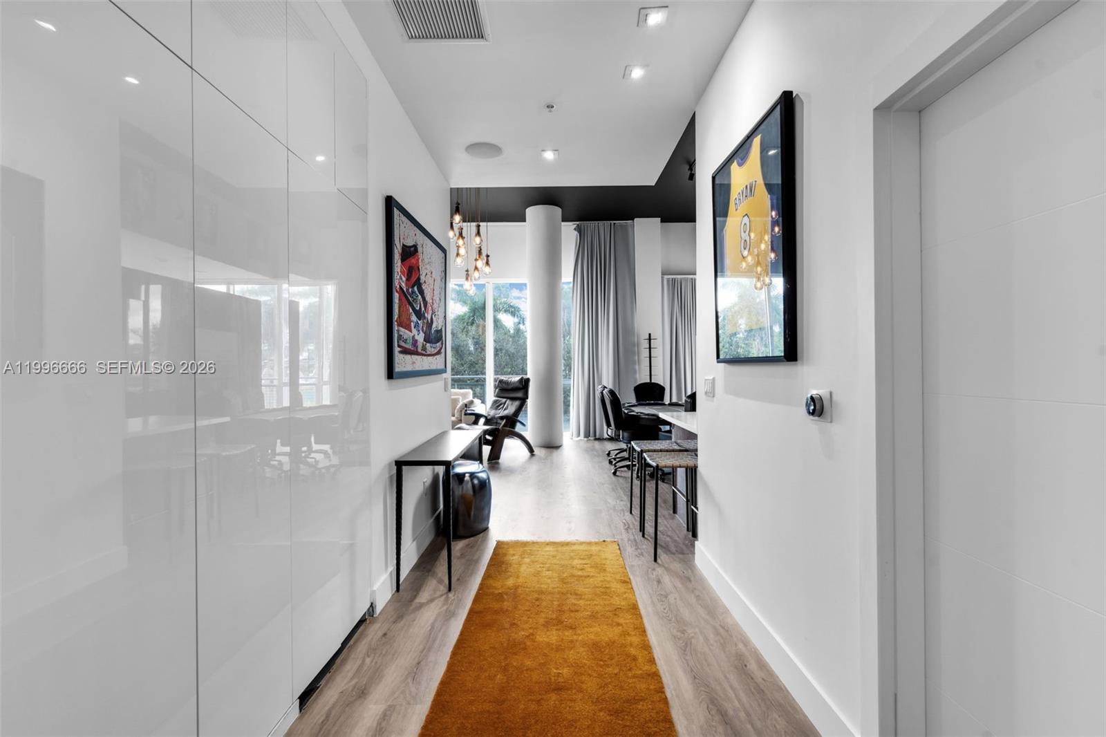A modern hallway with white cabinetry, wood flooring, and a framed basketball jersey on display — 244 Biscayne Blvd # 239, Miami FL 33132, MIAMI, FL