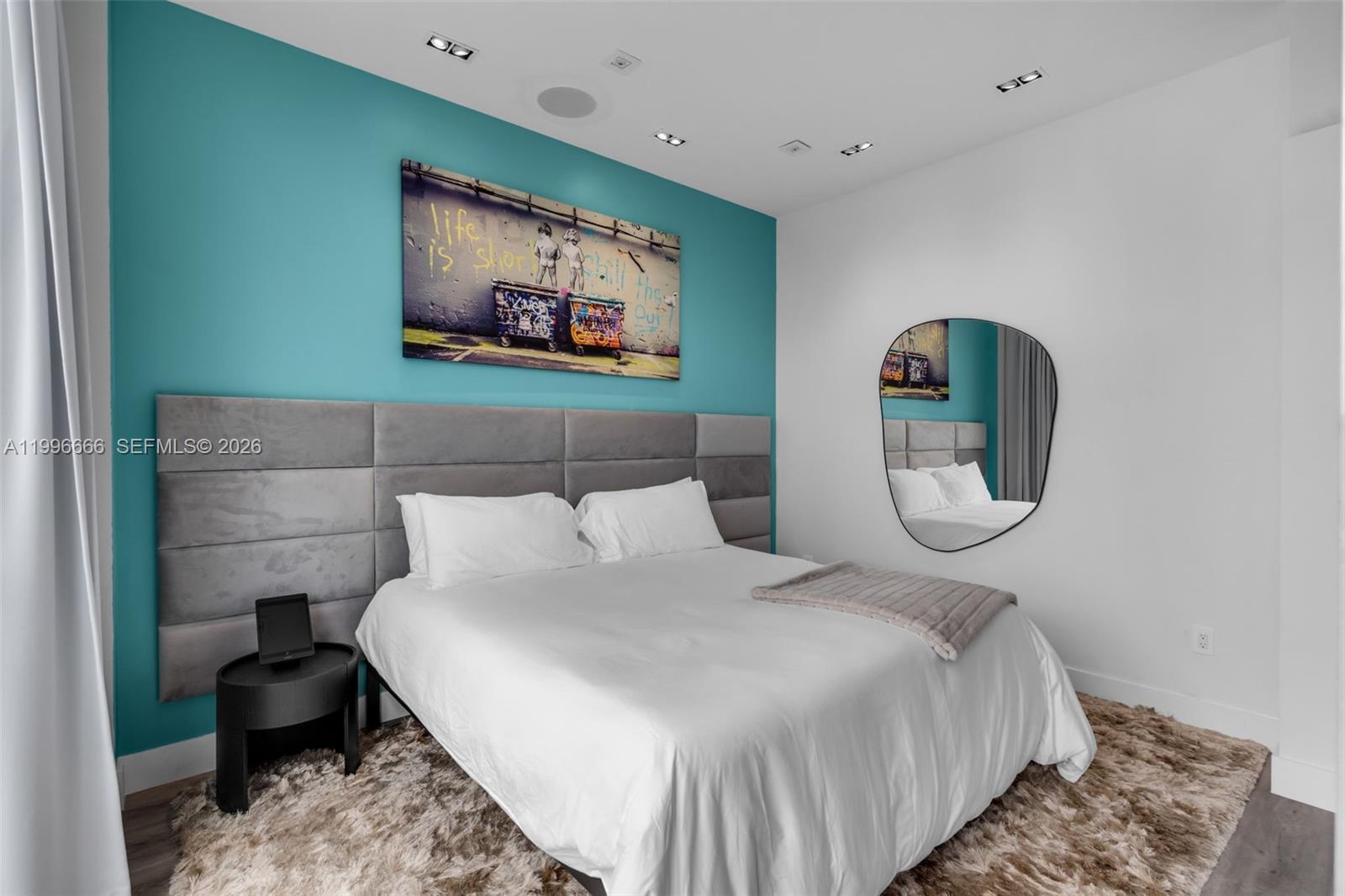 A bedroom features a teal accent wall, a grey upholstered headboard, and a shag rug — 244 Biscayne Blvd # 239, Miami FL 33132, MIAMI, FL