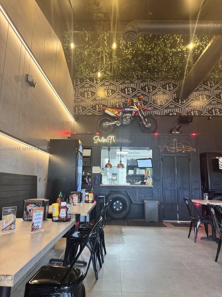This restaurant interior features a dirt bike mounted on the wall above a service window — 8205 NW 12th St, Doral FL 33126, DORAL, FL