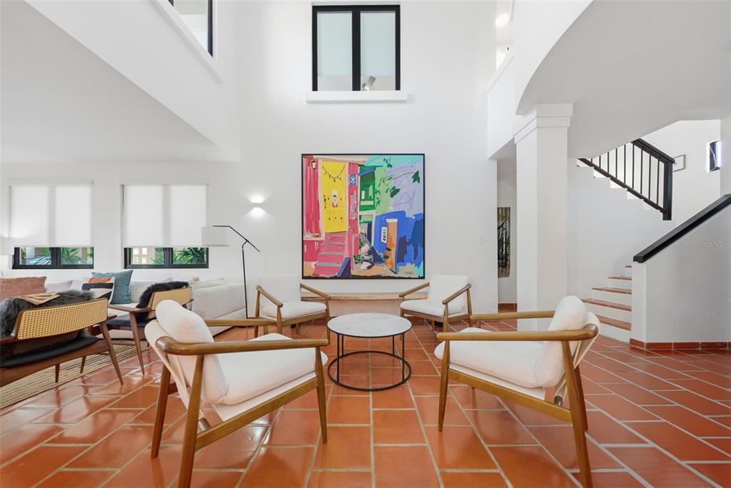 A bright living room features terracotta tile floors, a double-height ceiling, and modern armchairs — 86 LAKESIDE VILLAS UNIT H-3, VEGA ALTA, PR