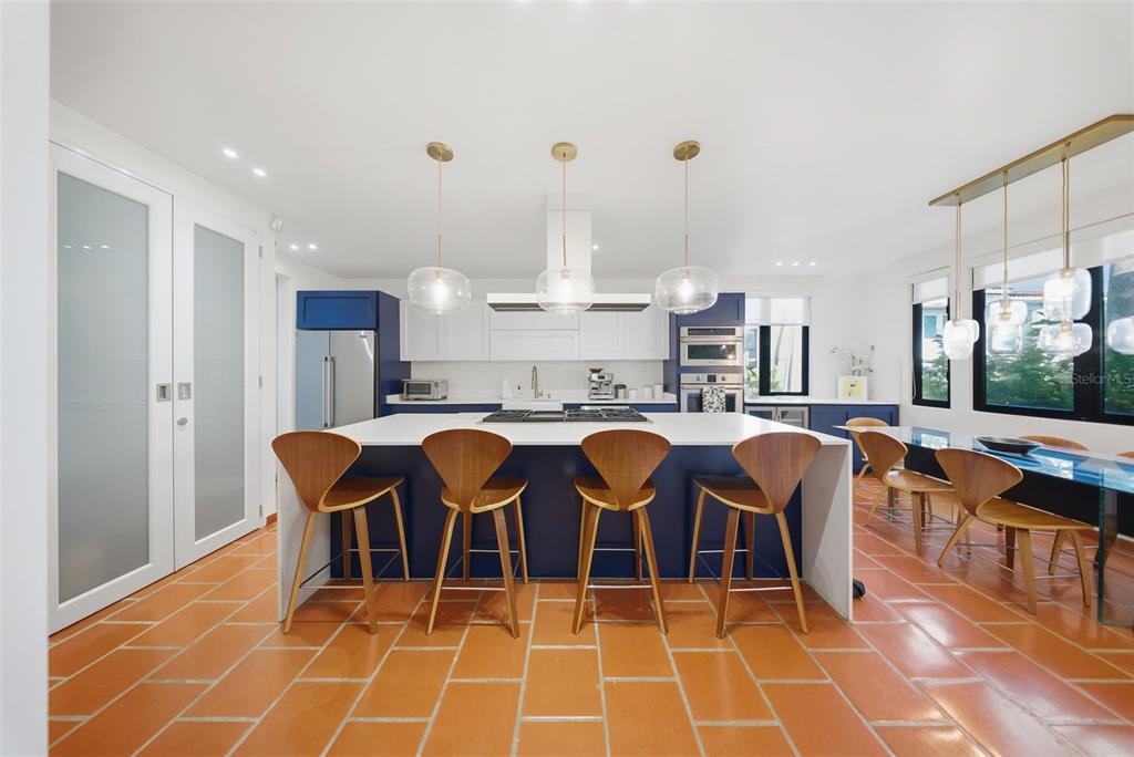 A modern kitchen features a large blue island with bar seating and terracotta tile flooring — 86 LAKESIDE VILLAS UNIT H-3, VEGA ALTA, PR