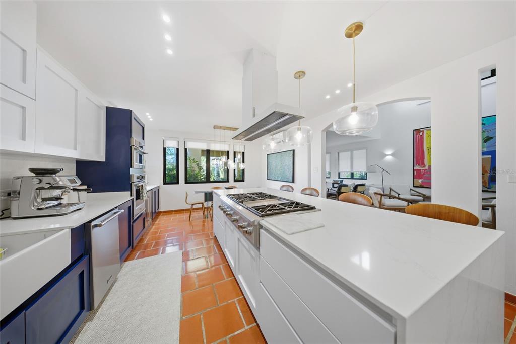 A modern kitchen features a large white island, blue cabinetry, and terracotta tile flooring — 86 LAKESIDE VILLAS UNIT H-3, VEGA ALTA, PR