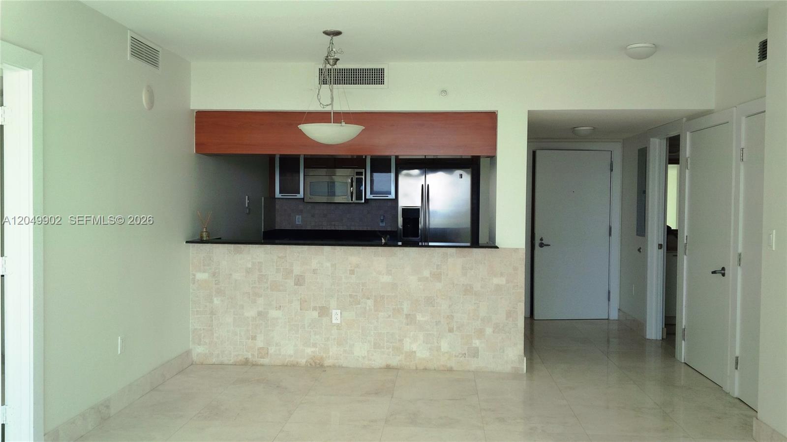 A kitchen with stainless steel appliances and a stone-tiled breakfast bar overlooks a dining area — 1800 N Bayshore Dr # 3310, Miami FL 33132, MIAMI, FL