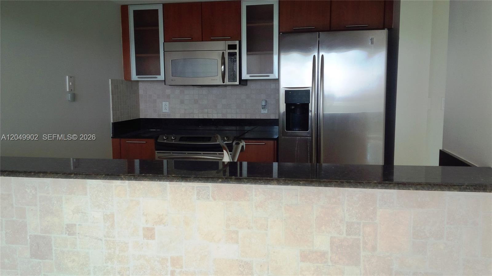 A kitchen features wood cabinets, stainless steel appliances, and a tiled breakfast bar — 1800 N Bayshore Dr # 3310, Miami FL 33132, MIAMI, FL