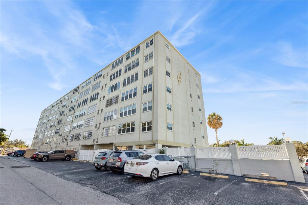 A multi-story apartment building with a parking lot and several parked cars in front — 7321 CENTRAL AVENUE UNIT 504, ST PETERSBURG, FL