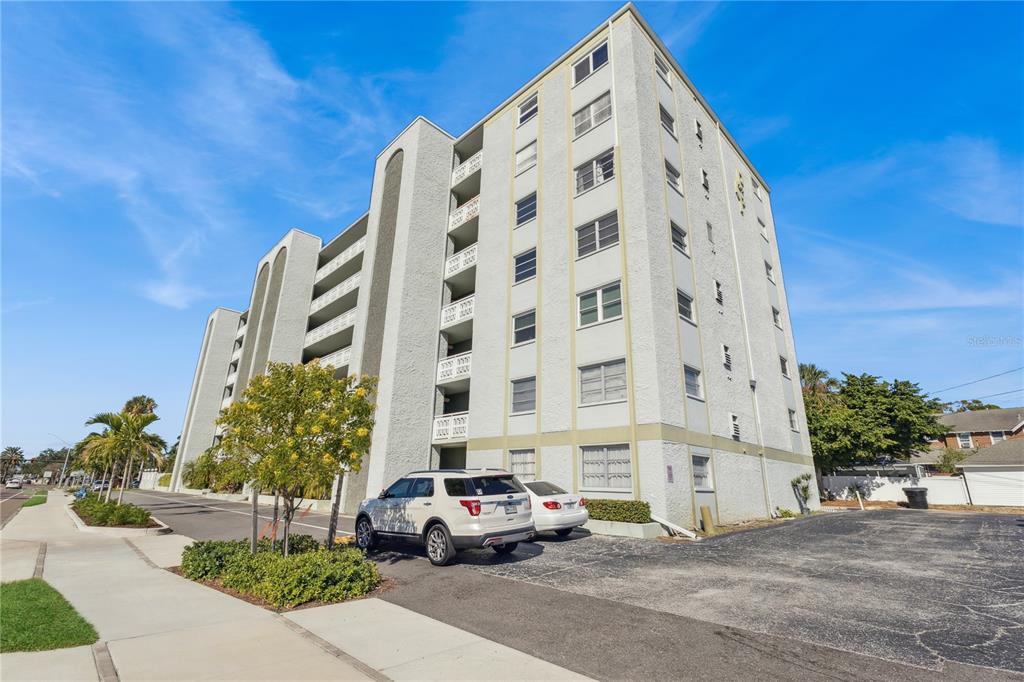 A multi-story apartment building with a parking lot and a white SUV in front — 7321 CENTRAL AVENUE UNIT 504, ST PETERSBURG, FL