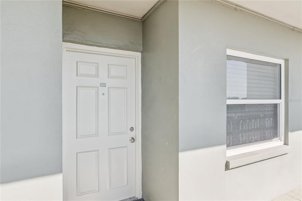 A white front door with the number 504 and a window on a gray exterior wall — 7321 CENTRAL AVENUE UNIT 504, ST PETERSBURG, FL