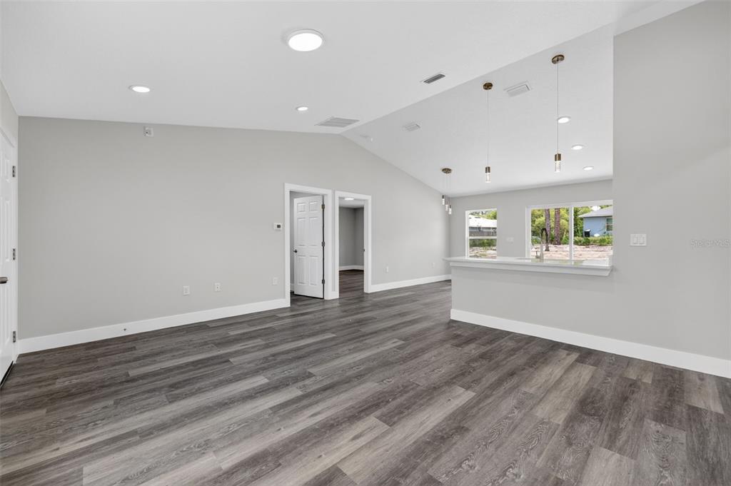 An open-concept living area features gray walls, dark wood-look flooring, and a kitchen breakfast bar — 1675 SW 159TH COURT, OCALA, FL