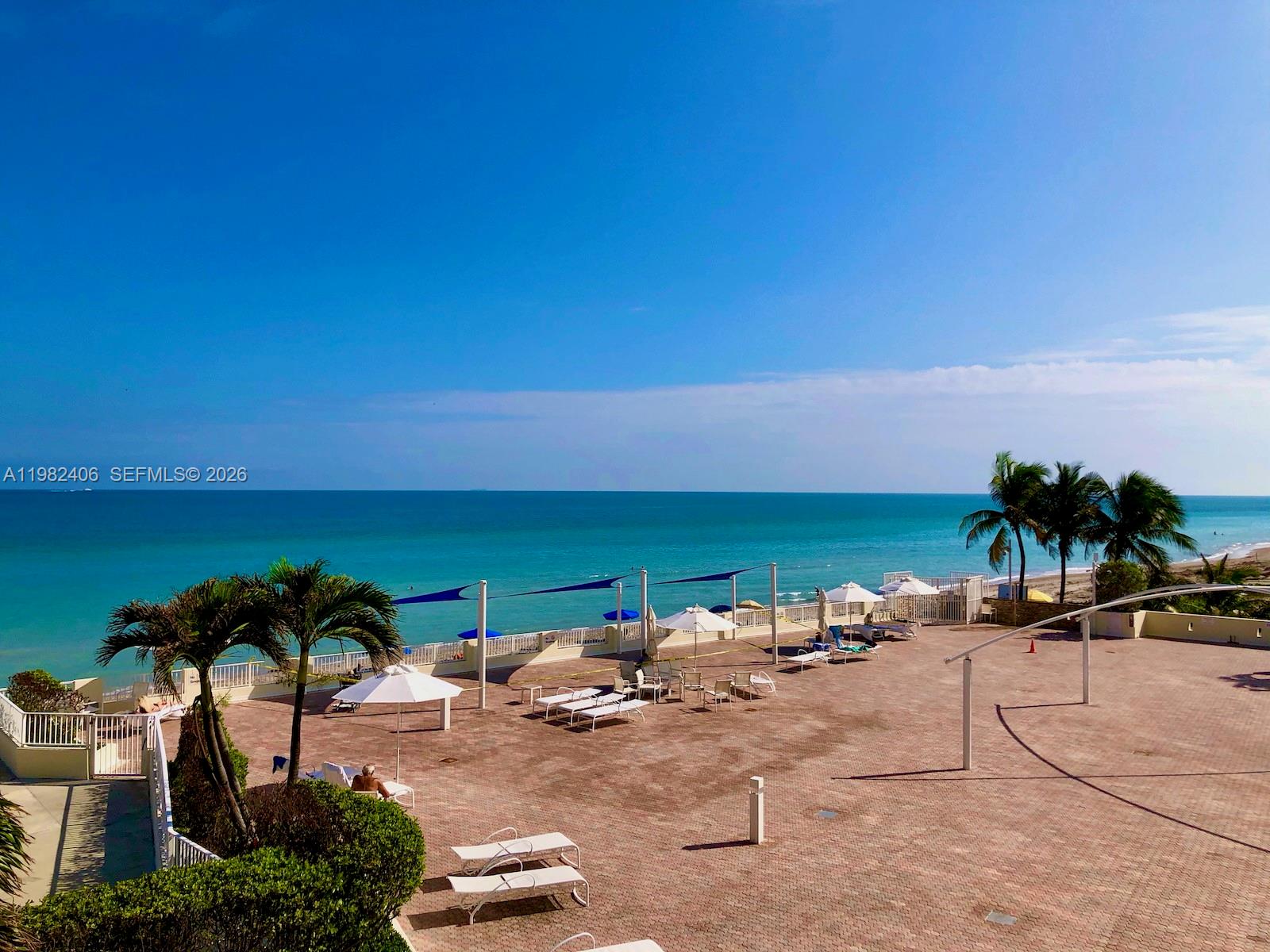 A balcony view overlooking a parking lot, a swimming pool area, and the ocean — 3180 S Ocean Dr # 401, Hallandale Beach FL 33009, HALLANDALE BEACH, FL