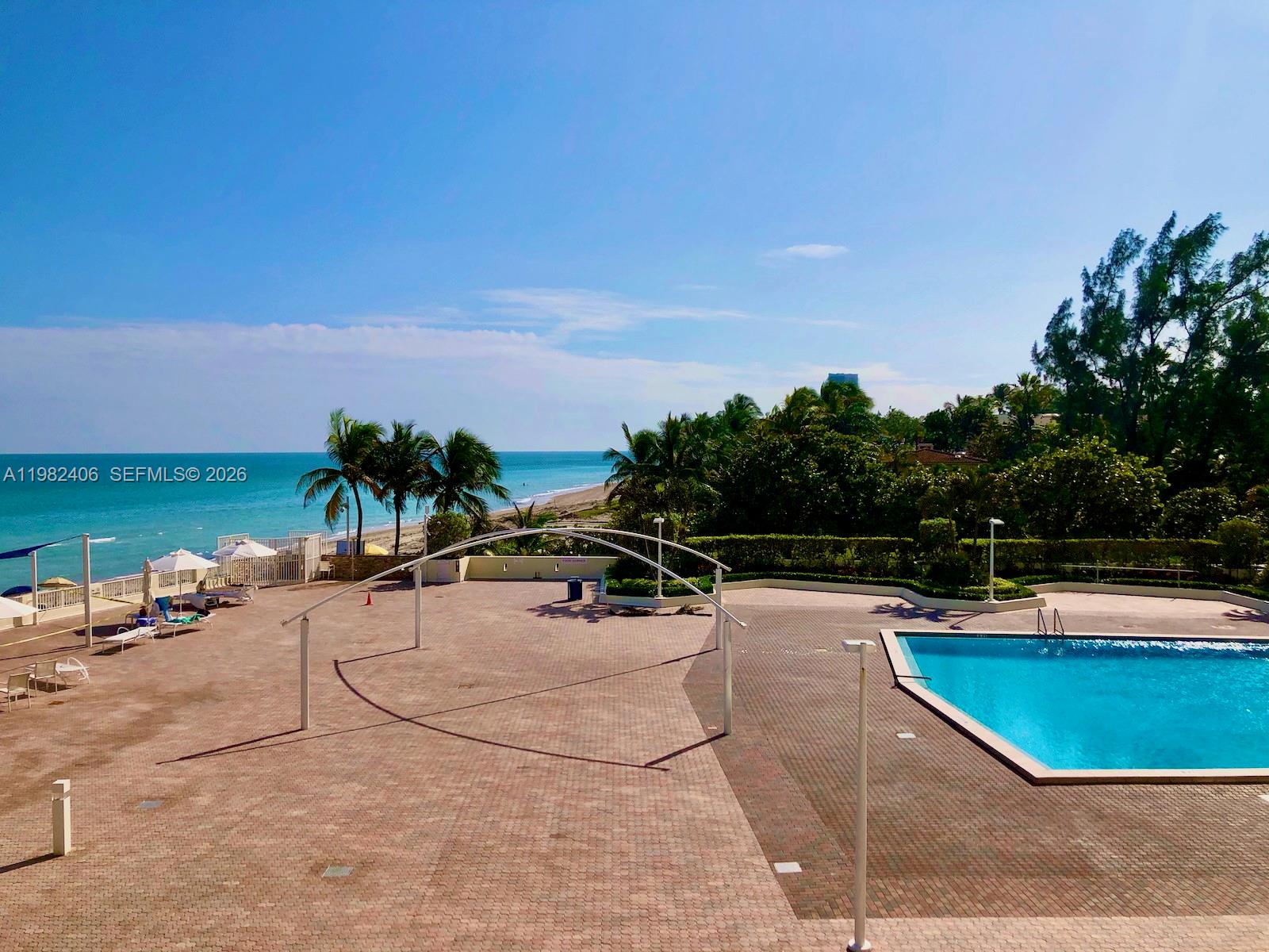 A view of the ocean and a swimming pool through a large glass sliding door — 3180 S Ocean Dr # 401, Hallandale Beach FL 33009, HALLANDALE BEACH, FL