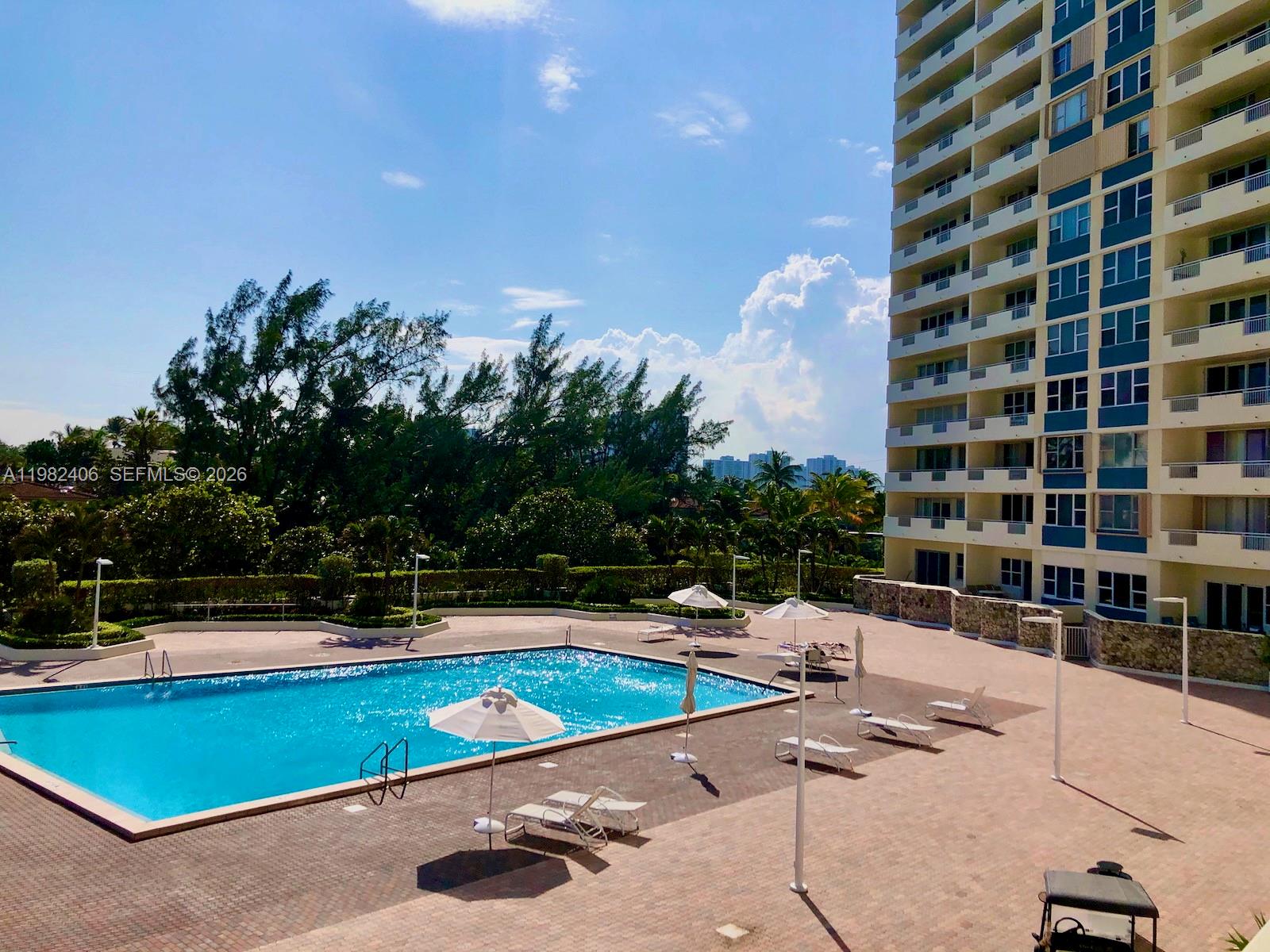 A balcony view overlooks a parking lot, a swimming pool, and the ocean — 3180 S Ocean Dr # 401, Hallandale Beach FL 33009, HALLANDALE BEACH, FL