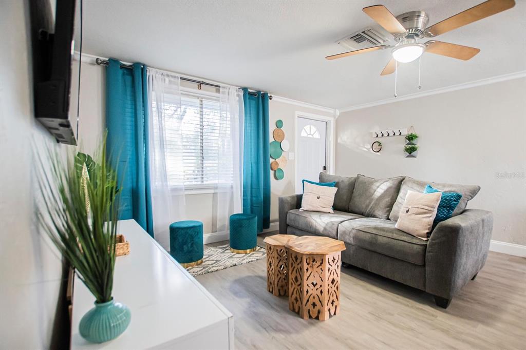 A living room features a gray sofa, two wooden side tables, and teal curtains — 4615 LORDS AVENUE, SARASOTA, FL