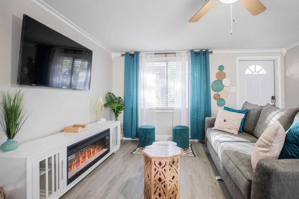 A living room features a fireplace media console, gray sofa, and teal curtains — 4615 LORDS AVENUE, SARASOTA, FL