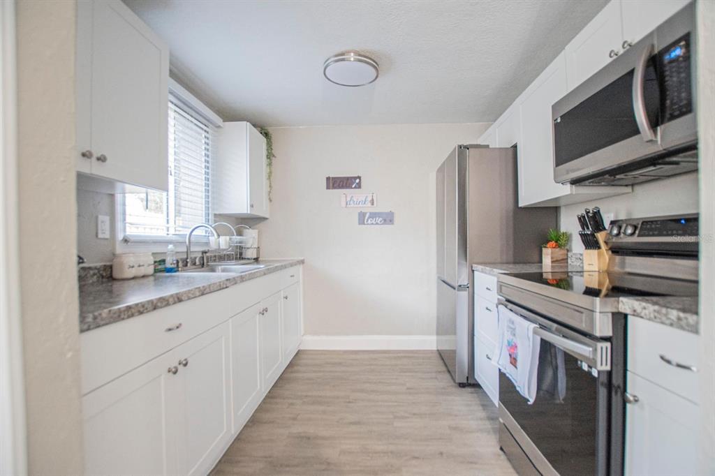 A galley kitchen features white cabinets, stainless steel appliances, and gray laminate countertops — 4615 LORDS AVENUE, SARASOTA, FL