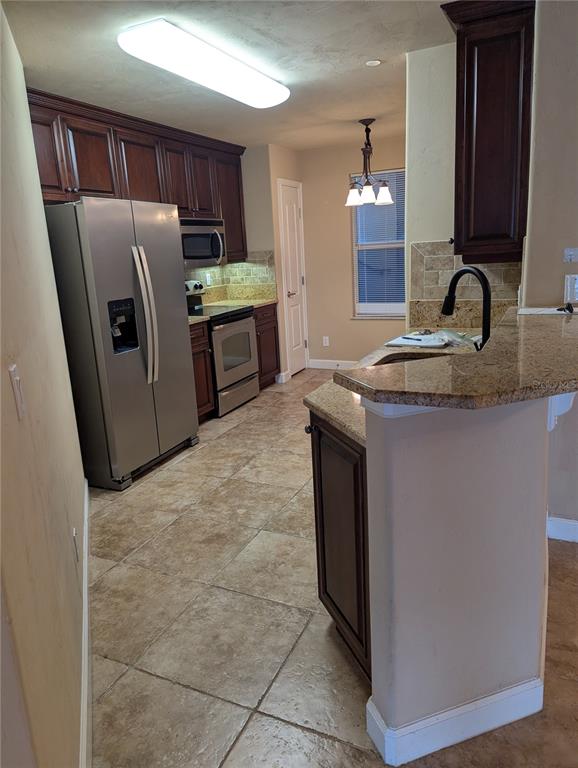 A kitchen features dark wood cabinets, granite countertops, stainless steel appliances, and tile flooring — 424 LUNA BELLA LANE UNIT 424, NEW SMYRNA BEACH, FL