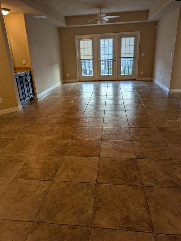 An empty room with large square floor tiles, a ceiling fan, and glass balcony doors — 424 LUNA BELLA LANE UNIT 424, NEW SMYRNA BEACH, FL