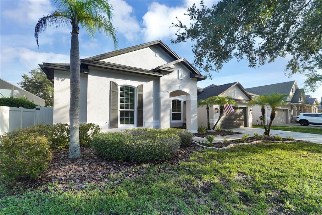 A single-story house with a palm tree, a front lawn, and a two-car garage — 7136 DERWENT GLEN CIRCLE, LAND O LAKES, FL
