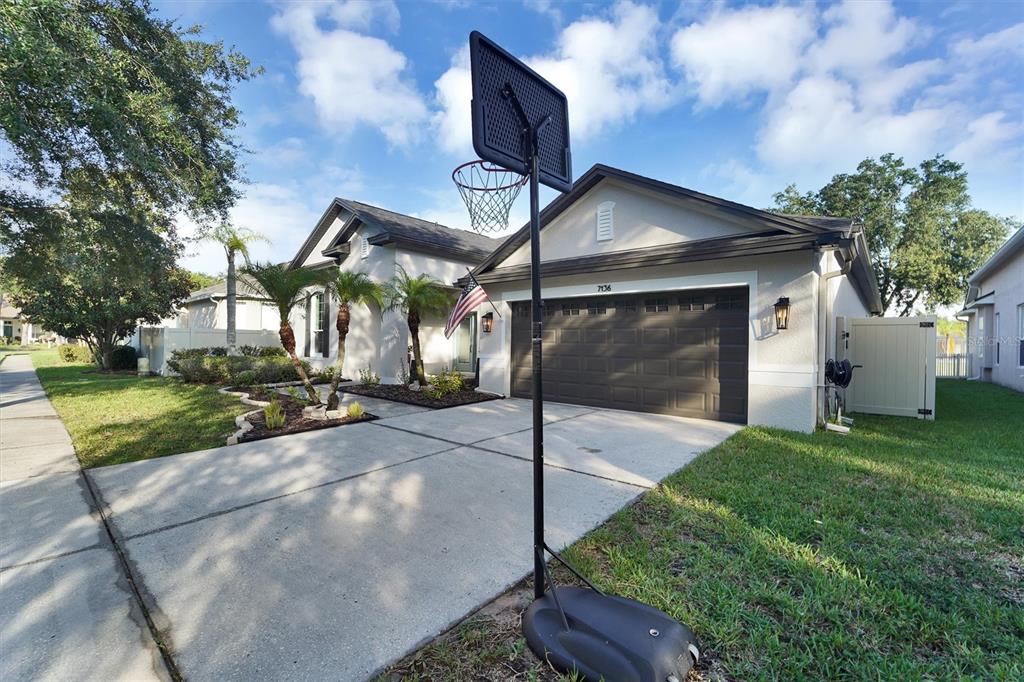 A single-story house with a two-car garage and a basketball hoop in the driveway — 7136 DERWENT GLEN CIRCLE, LAND O LAKES, FL