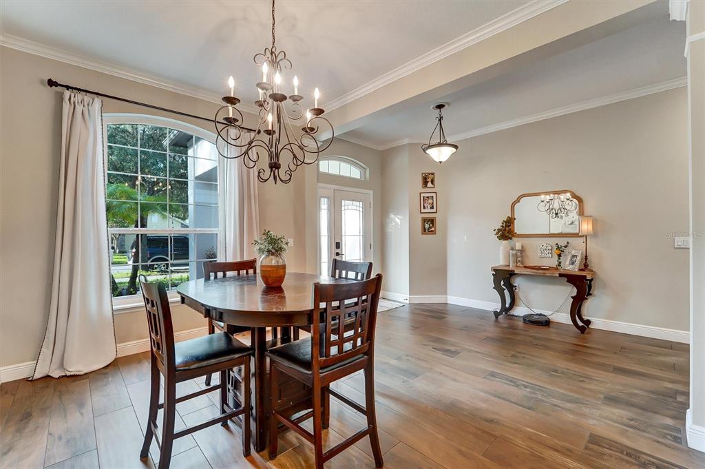 A dining area features a round wooden table, chandelier, and hardwood floors near an entryway — 7136 DERWENT GLEN CIRCLE, LAND O LAKES, FL