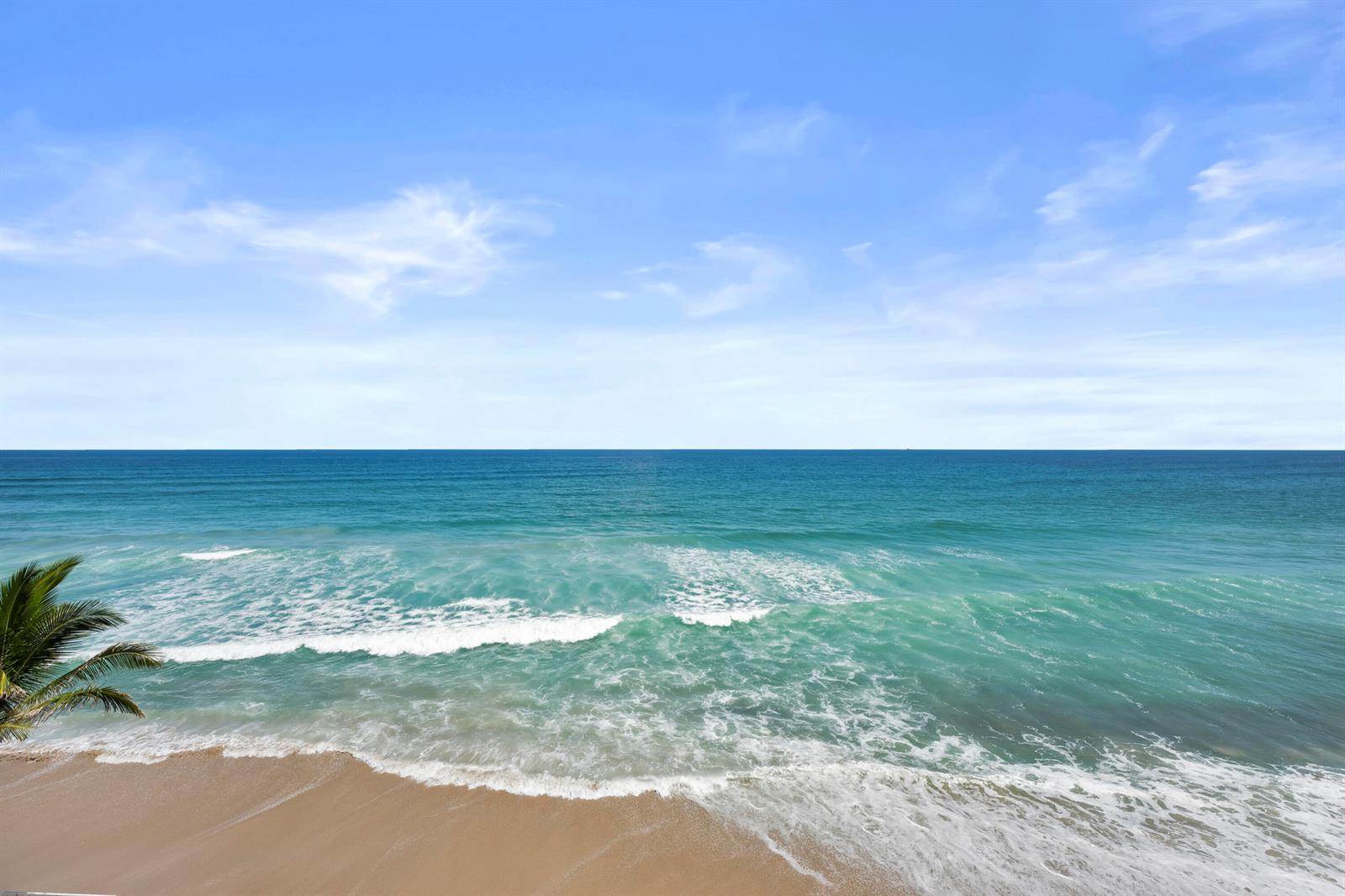 A high-angle view of a sandy beach with turquoise ocean waves under a blue sky — 3580 S Ocean Boulevard # 4c, South Palm Beach FL 33480, SOUTH PALM BEACH, FL