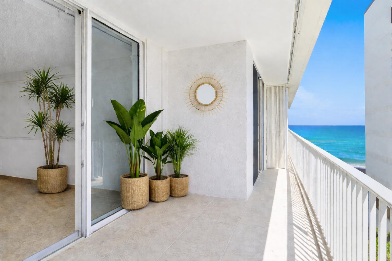 A balcony with potted plants, a sunburst mirror, and a view of the ocean — 3580 S Ocean Boulevard # 4c, South Palm Beach FL 33480, SOUTH PALM BEACH, FL