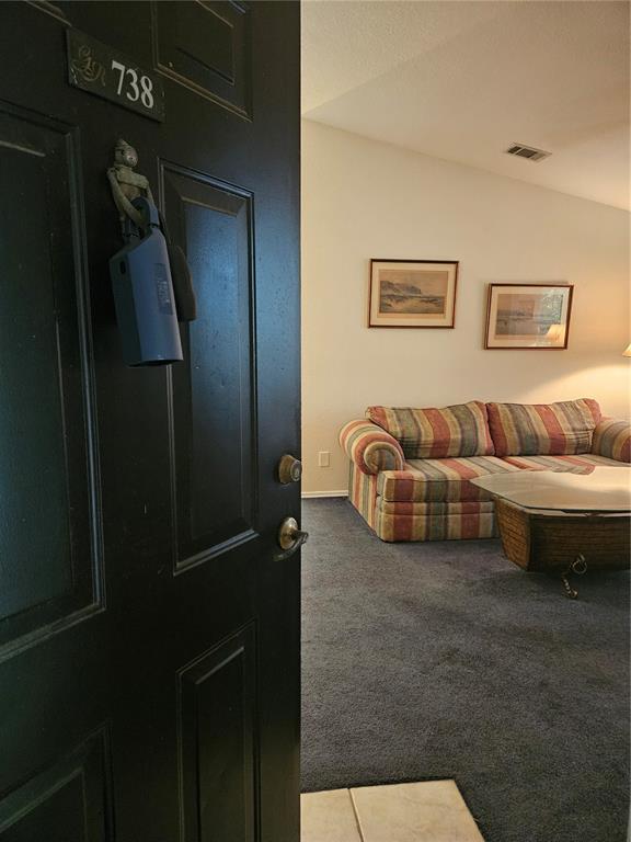 An open black door reveals a living room with a striped sofa and blue carpeting — 13810 SUTTON PARK DRIVE N UNIT 738, JACKSONVILLE, FL