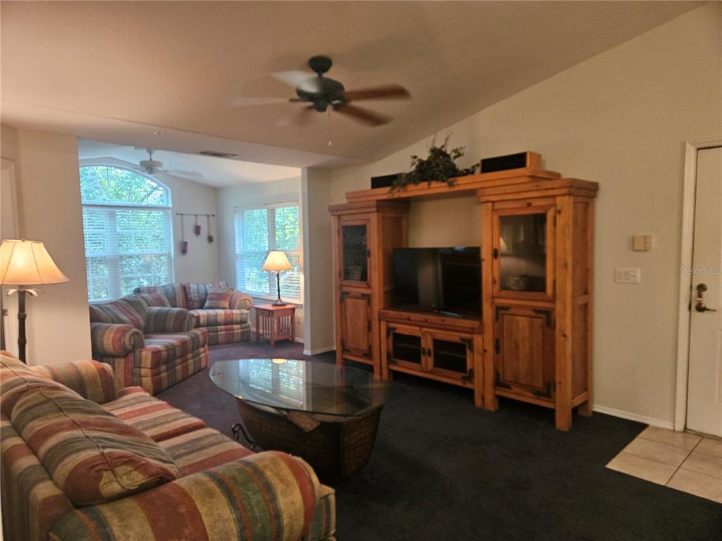 A living room features a large wooden entertainment center, striped sofas, and a glass coffee table — 13810 SUTTON PARK DRIVE N UNIT 738, JACKSONVILLE, FL