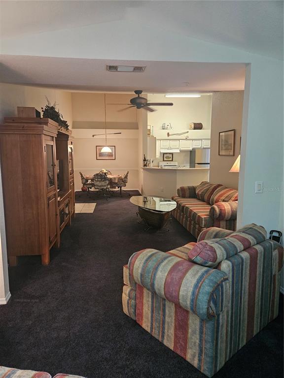 A living room with dark carpet leads to a dining area and an open kitchen — 13810 SUTTON PARK DRIVE N UNIT 738, JACKSONVILLE, FL