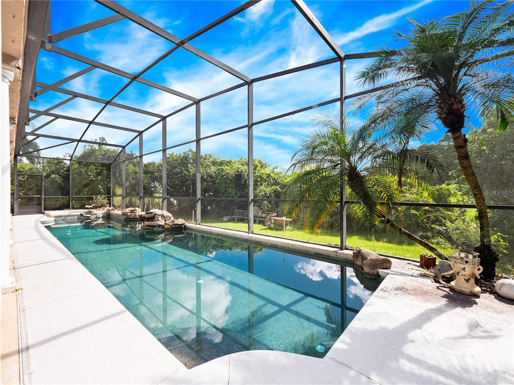 A rectangular swimming pool with rock features is enclosed by a screened lanai — 2072 STONE CROSS CIRCLE, ORLANDO, FL