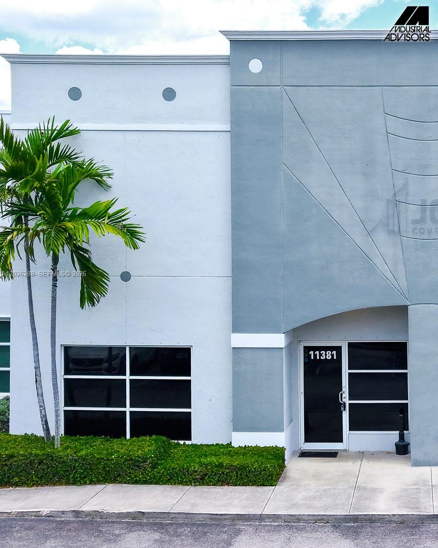The exterior of a commercial building features a palm tree, a glass door, and windows — 11381 NW 122nd St # 10, Medley FL 33178, MEDLEY, FL