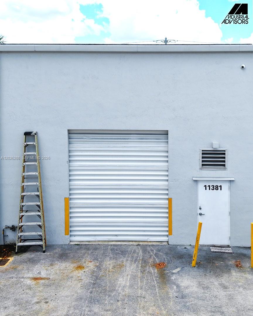 An exterior view of a warehouse building featuring a roll-up door and a pedestrian door — 11381 NW 122nd St # 10, Medley FL 33178, MEDLEY, FL