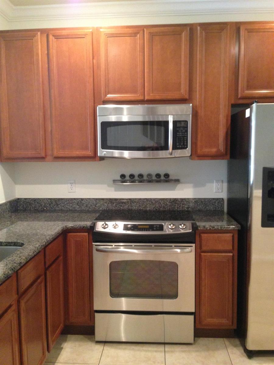 A kitchen features wood cabinets, stainless steel appliances, and granite countertops — 9680 Lago Drive # 9680, Boynton Beach FL 33472, BOYNTON BEACH, FL