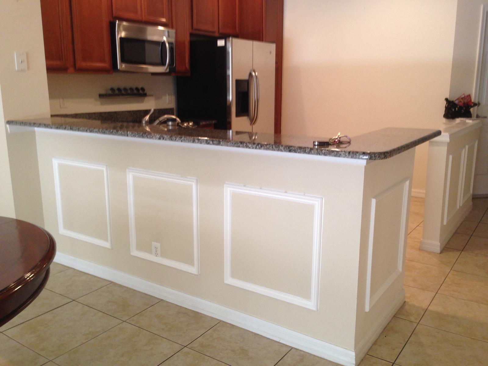 A kitchen island with granite countertops and white wainscoting faces a dining area — 9680 Lago Drive # 9680, Boynton Beach FL 33472, BOYNTON BEACH, FL