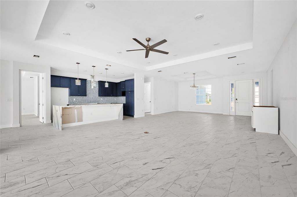 An open-concept living area features a kitchen with blue cabinets and white marble-look tile flooring — 9024 EVELYN ROAD, ENGLEWOOD, FL