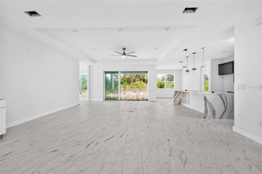 An open-concept living area features light marble-look tile flooring, a tray ceiling, and a kitchen island — 9024 EVELYN ROAD, ENGLEWOOD, FL