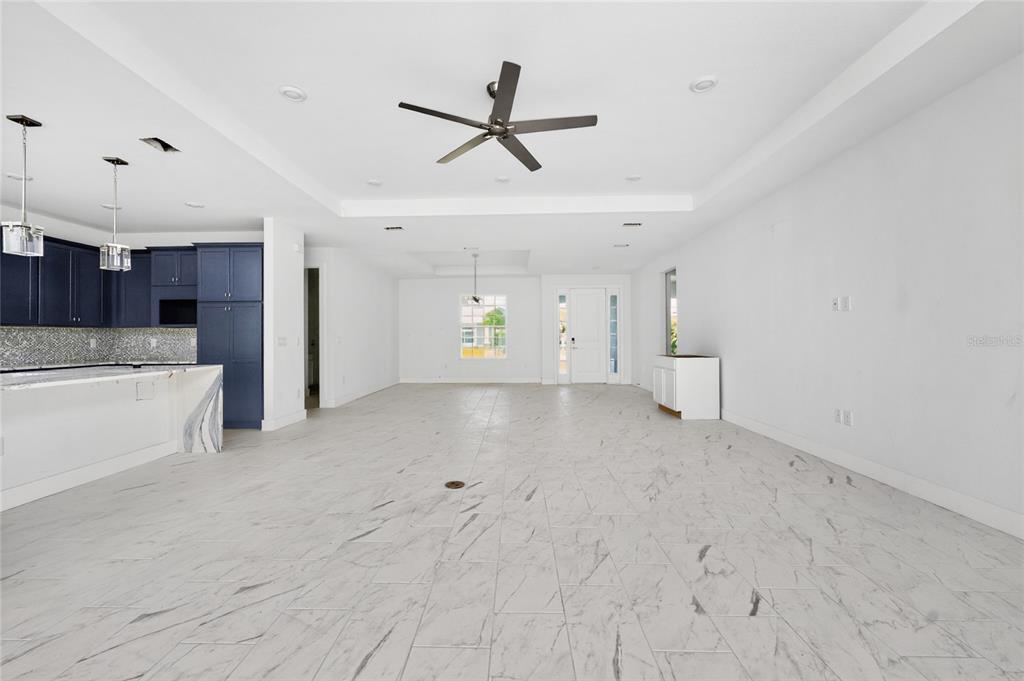 An open-concept living area features white marble-look tile floors, a dark blue kitchen, and recessed lighting — 9024 EVELYN ROAD, ENGLEWOOD, FL