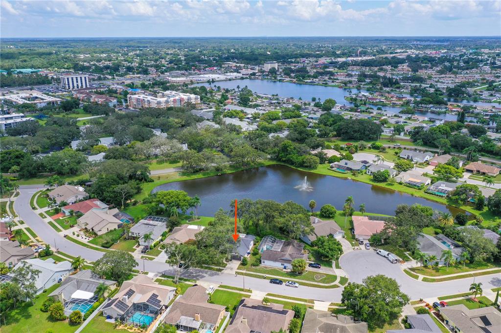 An aerial view shows a suburban house with a red arrow pointing to its roof — 2906 WINDRIDGE DRIVE, HOLIDAY, FL