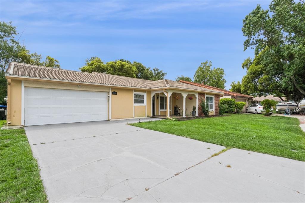 A single-story house with a beige exterior, a two-car garage, and a concrete driveway — 5246 MAYAPPLE CIRCLE, ORLANDO, FL
