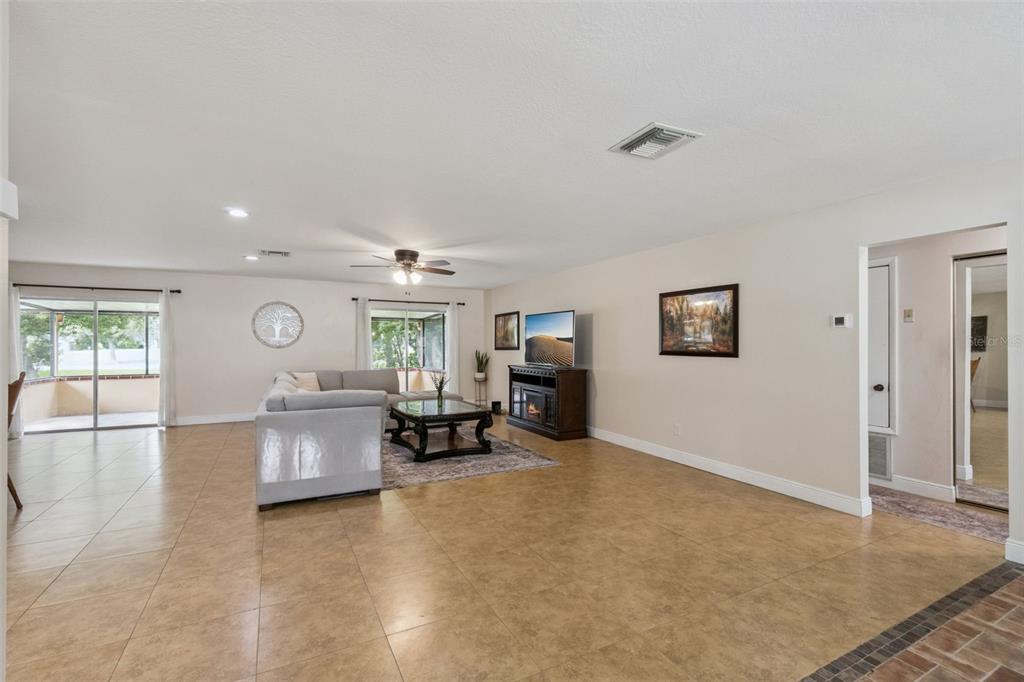 A spacious living room features tile flooring, a sectional sofa, and a television console — 5246 MAYAPPLE CIRCLE, ORLANDO, FL