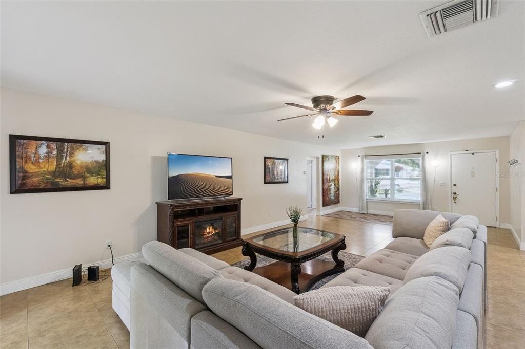 A living room features a large sectional sofa, a fireplace media console, and tile flooring — 5246 MAYAPPLE CIRCLE, ORLANDO, FL