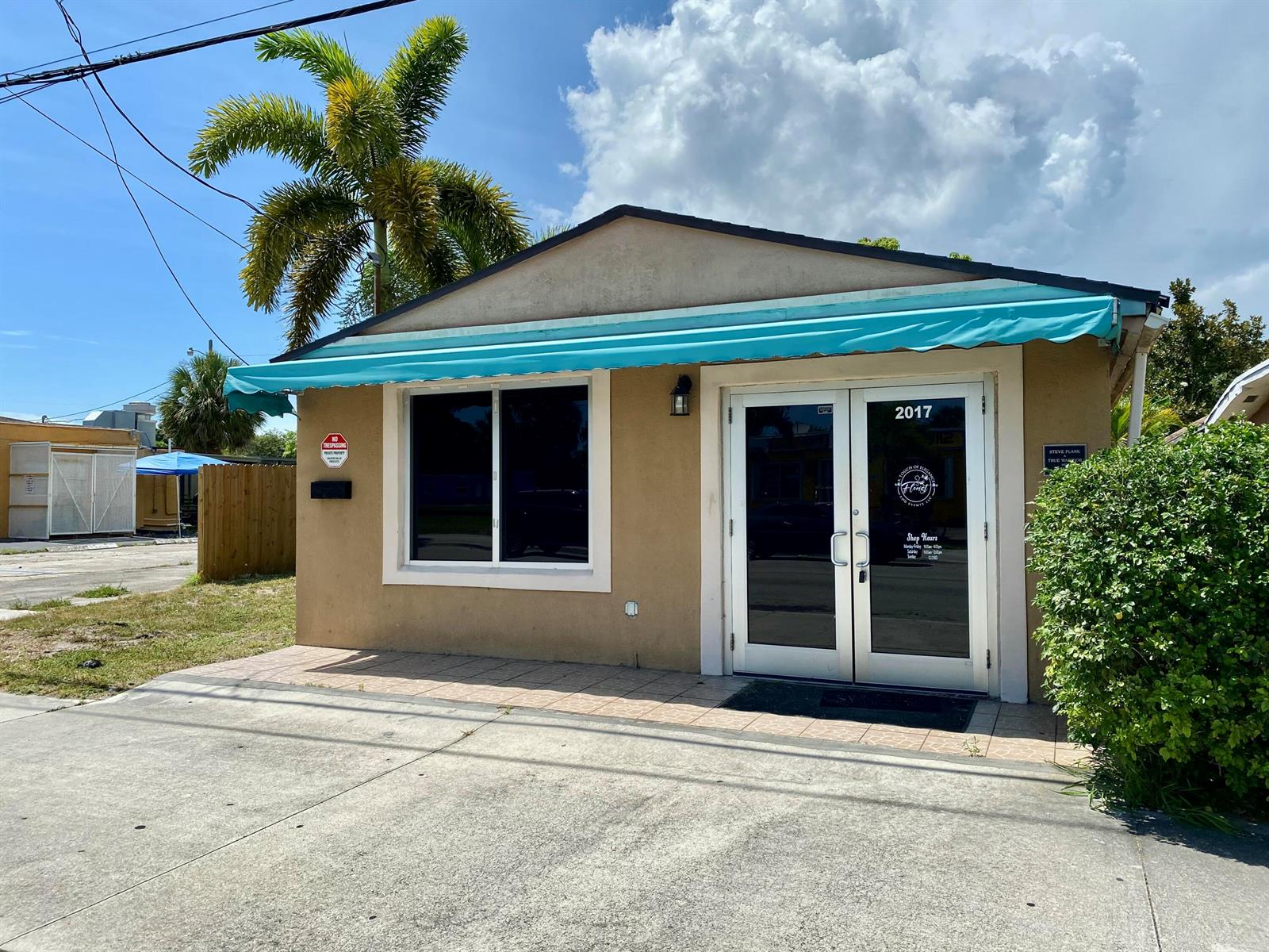 A tan commercial building features a teal awning, glass double doors, and a palm tree — 2017 Ave D, Fort Pierce FL 34950, FORT PIERCE, FL