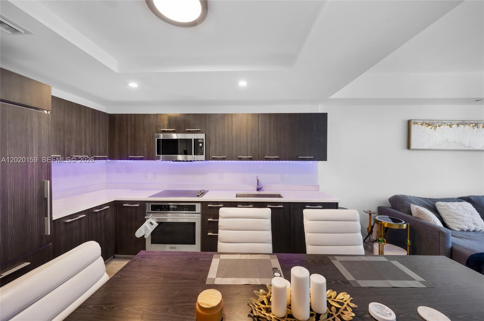 A modern kitchen features dark wood cabinetry, white countertops, and under-cabinet purple lighting — 55 SW 9th St # 1804, Miami FL 33130, MIAMI, FL