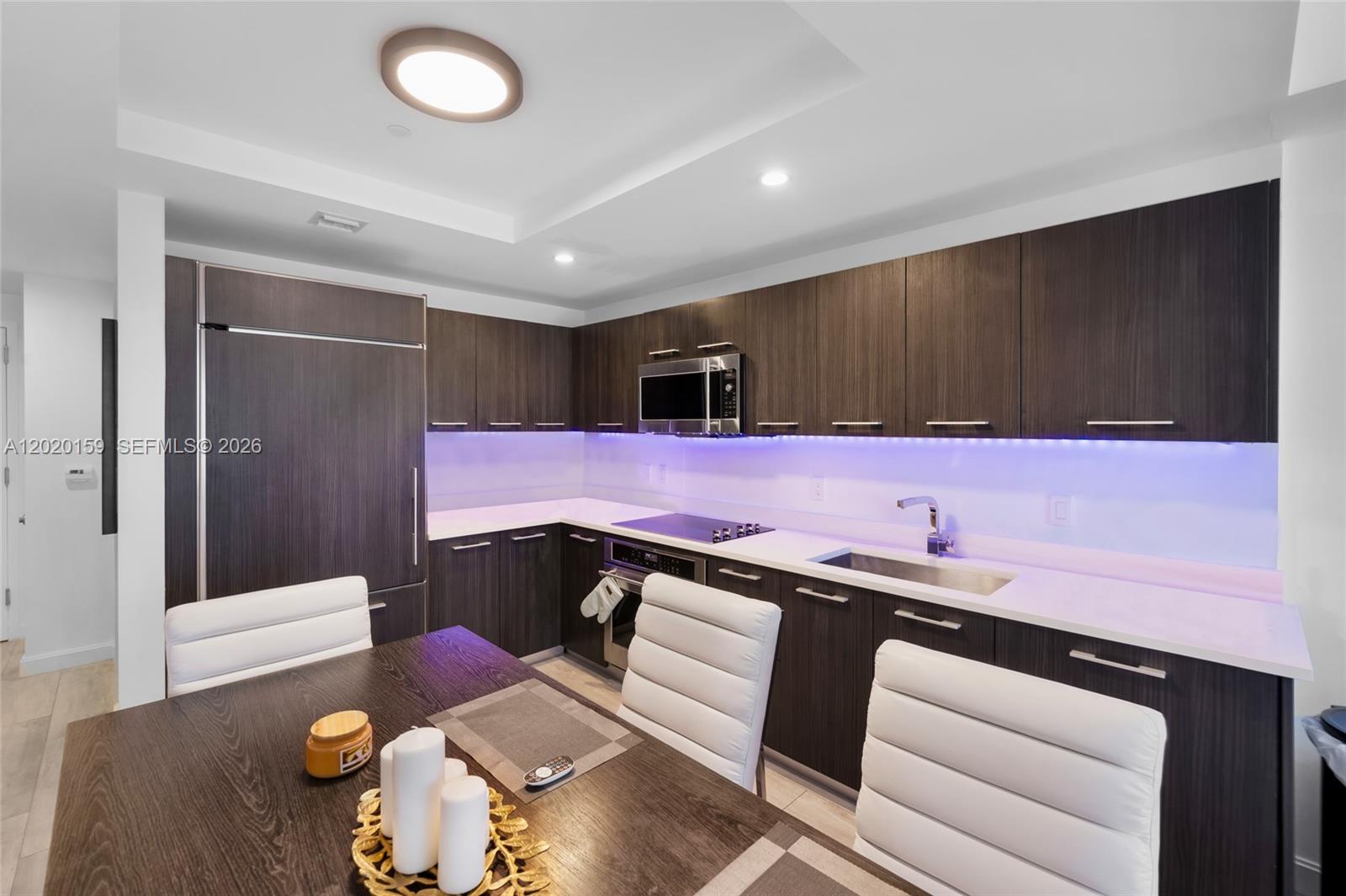 A modern kitchen features dark wood cabinetry, white countertops, and under-cabinet purple lighting — 55 SW 9th St # 1804, Miami FL 33130, MIAMI, FL