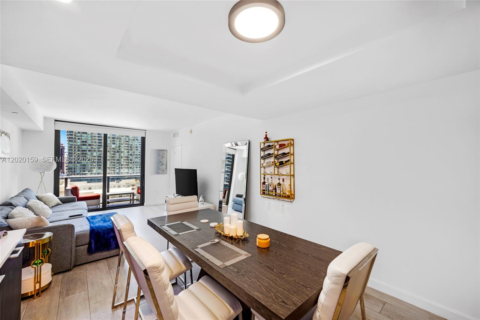 A dining area with a dark wood table and white chairs sits beside a living room — 55 SW 9th St # 1804, Miami FL 33130, MIAMI, FL