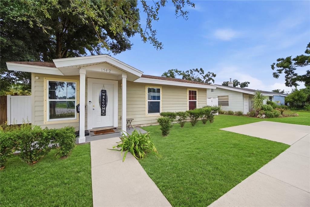 A single-story house with light green siding, a white front door, and a concrete walkway — 1542 28TH STREET S, ST PETERSBURG, FL