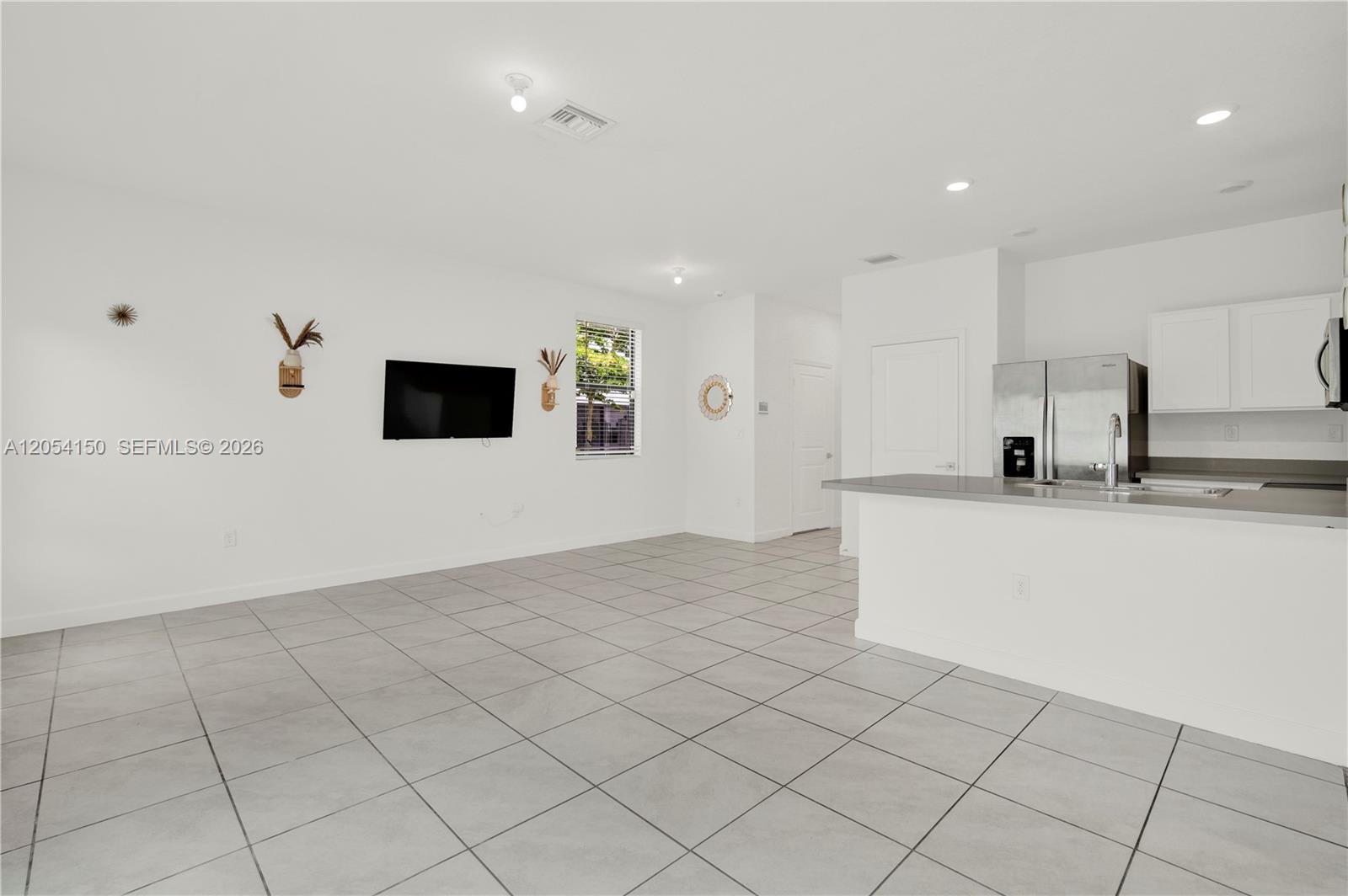 A bright, open-concept living area features white walls, tile flooring, and an adjacent kitchen — 1161 SW 8th Ave, Florida City FL 33034, FLORIDA CITY, FL