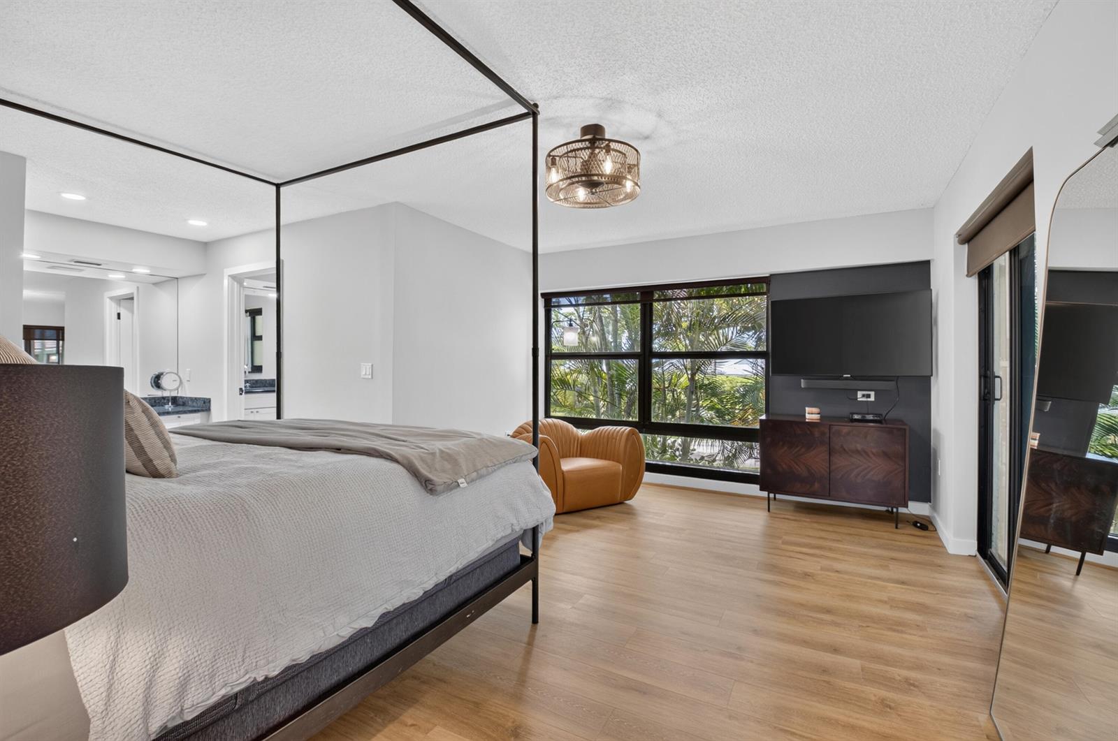 A bedroom features a canopy bed, a wall-mounted television, and a large window with greenery — 6760 Willow Wood Drive # 1206, Boca Raton FL 33434, BOCA RATON, FL