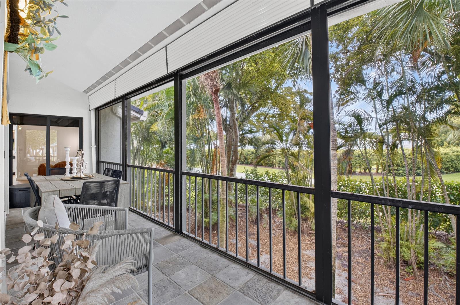 A screened-in patio features tile flooring, outdoor dining furniture, and views of lush tropical landscaping — 6760 Willow Wood Drive # 1206, Boca Raton FL 33434, BOCA RATON, FL